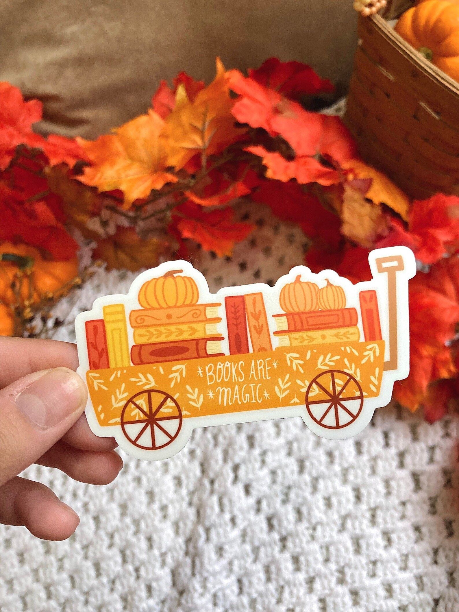 sticker of a wagon full of books and pumpkins saying books are magic