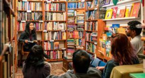 a group of people seated at a bookstore with one person leading the conversation