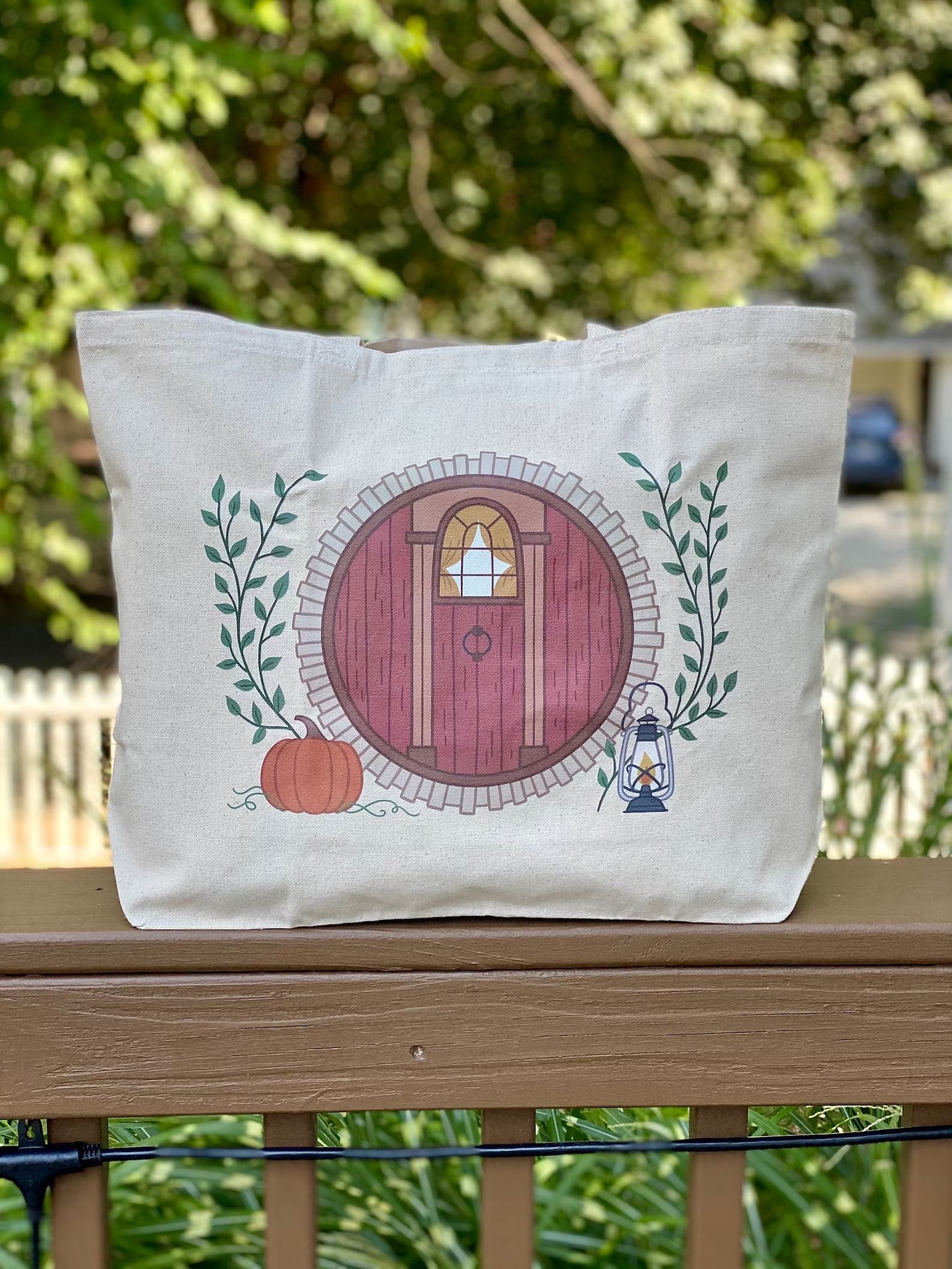totebag with the circular door of a hobbit house with a pumpkin and lantern