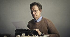 white man typing on an older typewriter