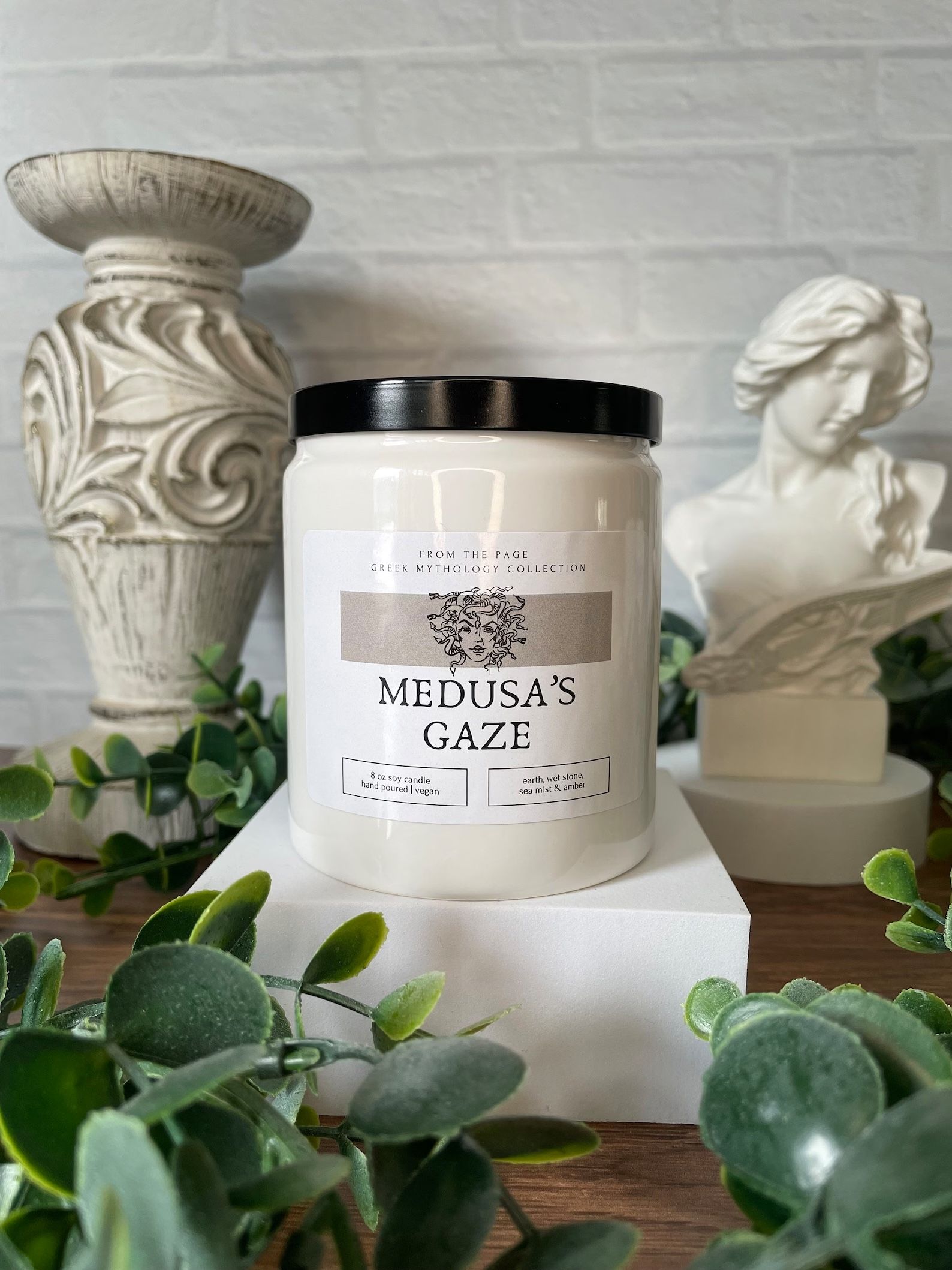 cream-colored candle with a label that reads "Medusas's Gaze"