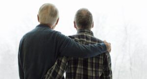 two older men seen embracing from behind