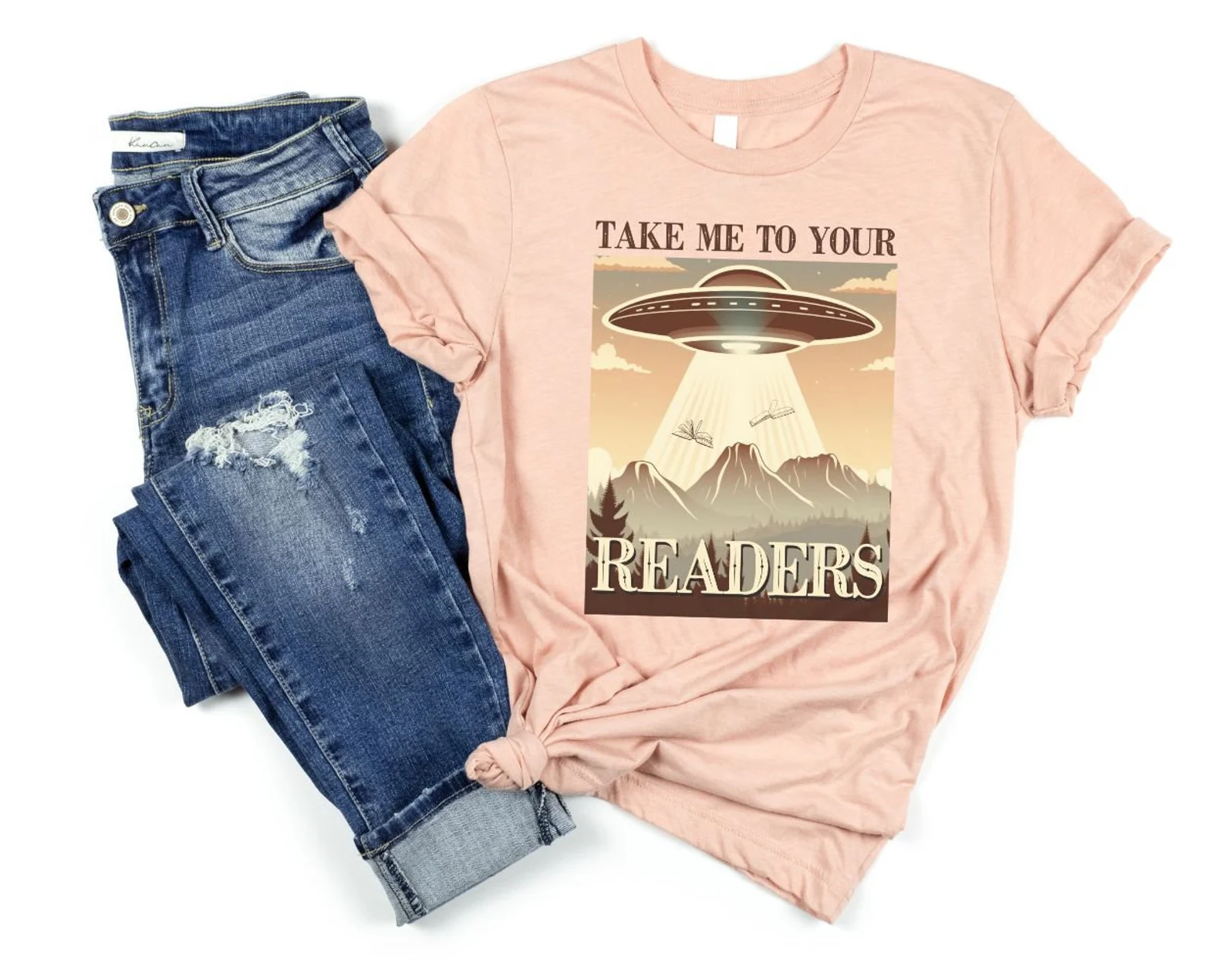 Image of a pink t-shirt with a UFO and the words "take me to your readers."