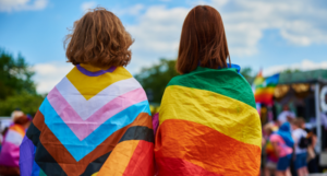 two young people wearing a pride flag