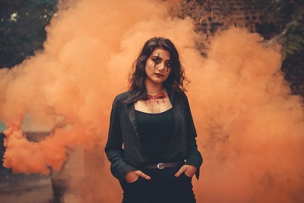  photo of a person wearing creepy clown makeup against an orange smoky background