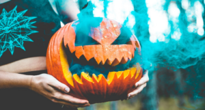 a photo of someone holding a jack o'lantern with green smoke billowing from it