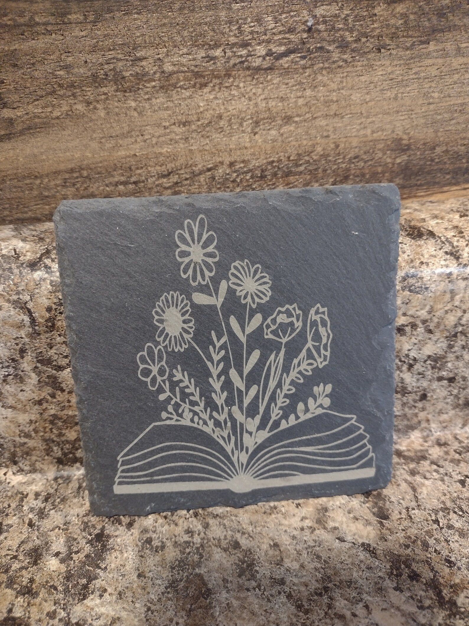Flower and Book stone coaster is in front of a granite countertop.