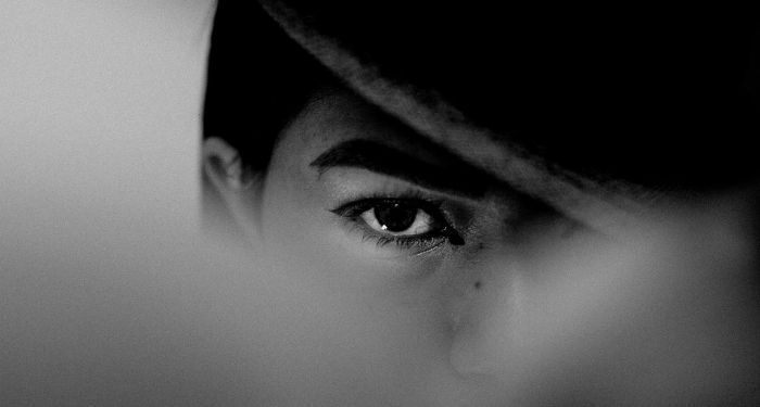 black and white photo of a person with fair skin looking with heir hat pulled low