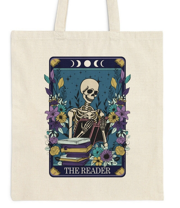 beige tote bag with a graphic print image to look like a tarot card with a skeleton reading a book