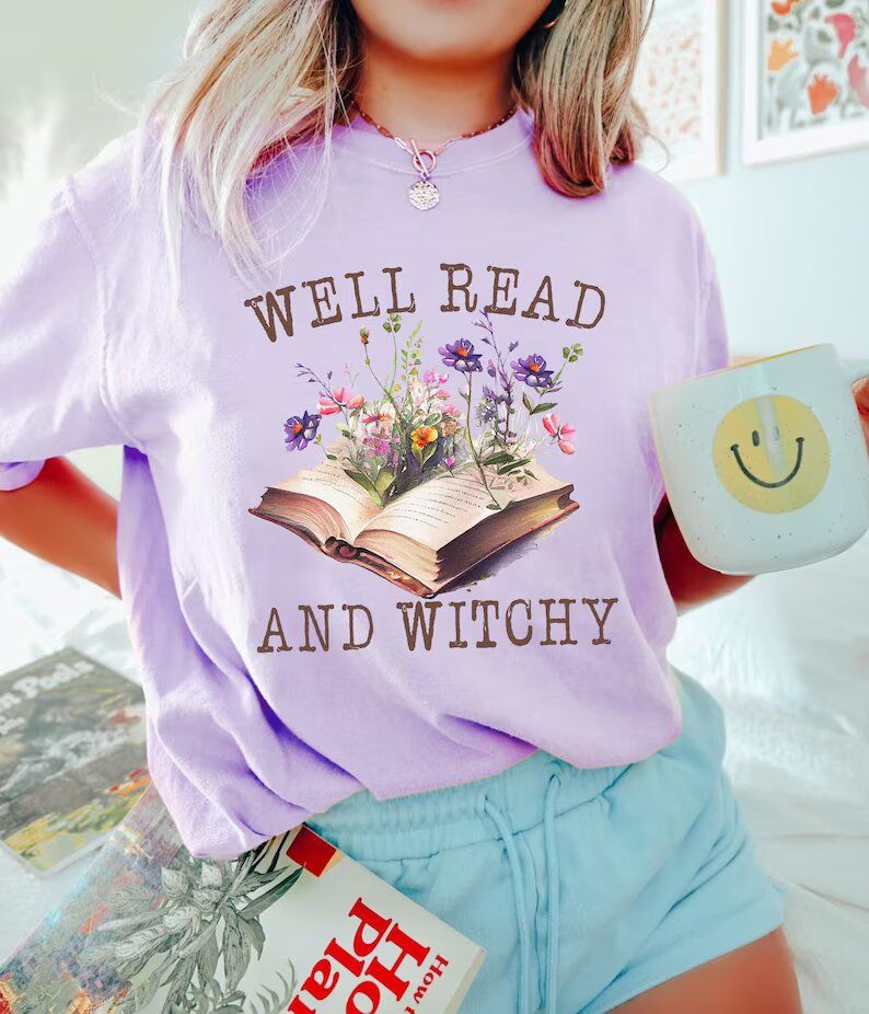 T-shirt that reads "Well read and witchy." It has a painting of an open book with flowers sprouting from it.