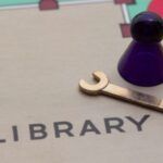 a board game with a game piece, a small silver wrench placed in a section labeled "library"