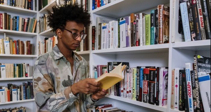 brown-skinned Black man with kinky fro reading in a library