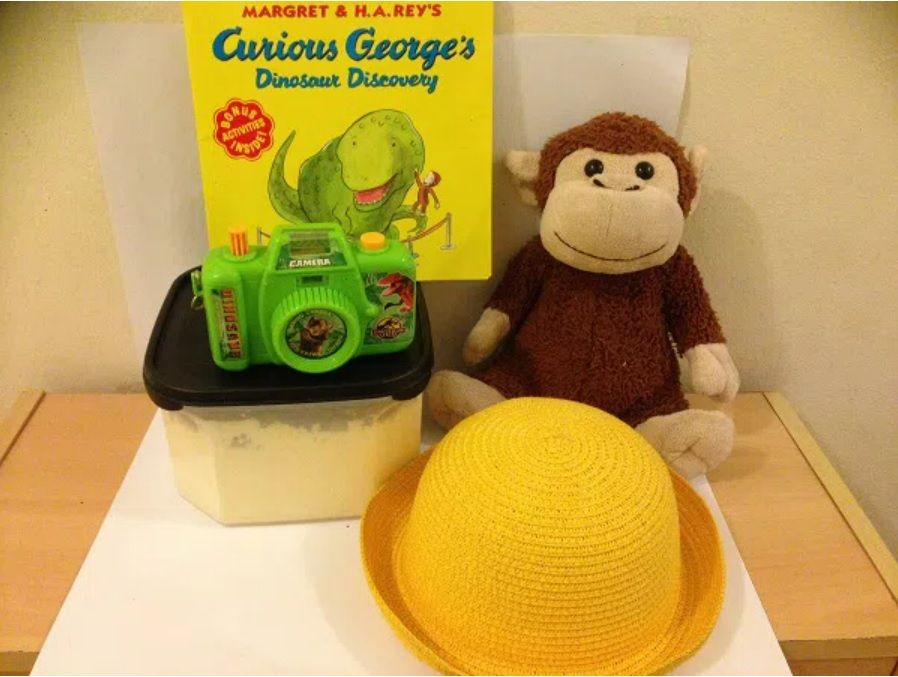 image of items used in a curious george cosplay, including plush toy monkey and yellow hat
