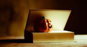 a small ceramic jack-o-lantern resting inside the pages of a book