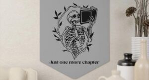 A hanging wall banner with an illustration of a skeleton reading a book and the text "Just one more chapter"