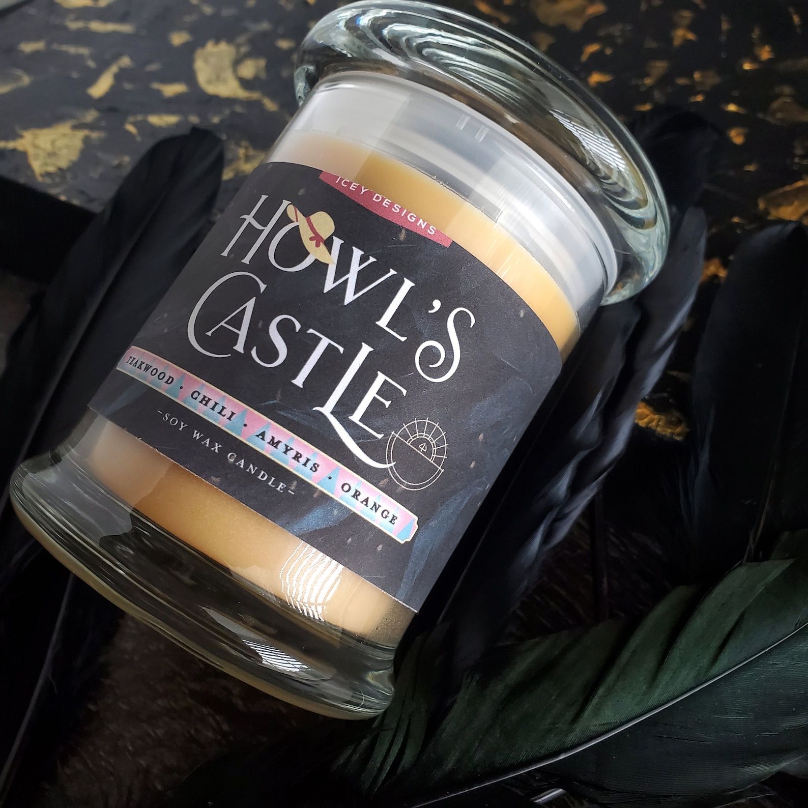 A glass jar holding a tan candle with a label that says "Howl's Castle"