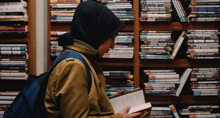 light tan skinned woman in hijab looking at books in a store