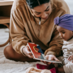 a photo of a Black mother and baby reading a board book