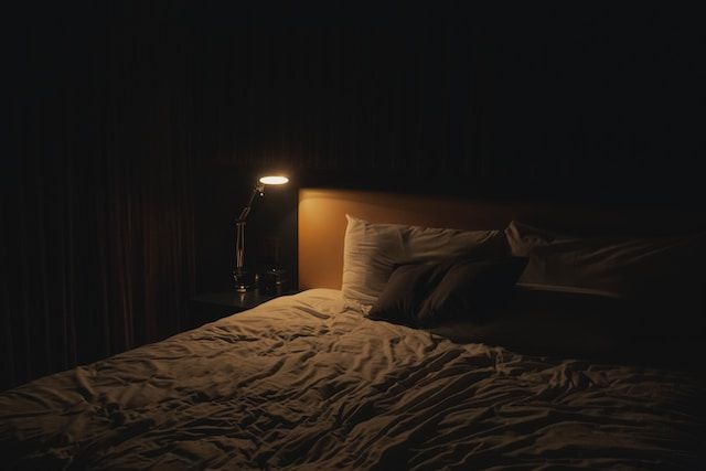 Dark bedroom with a reading light illuminating a small space on the bed