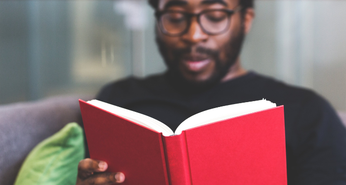 a photo of a Black man reading on a couch