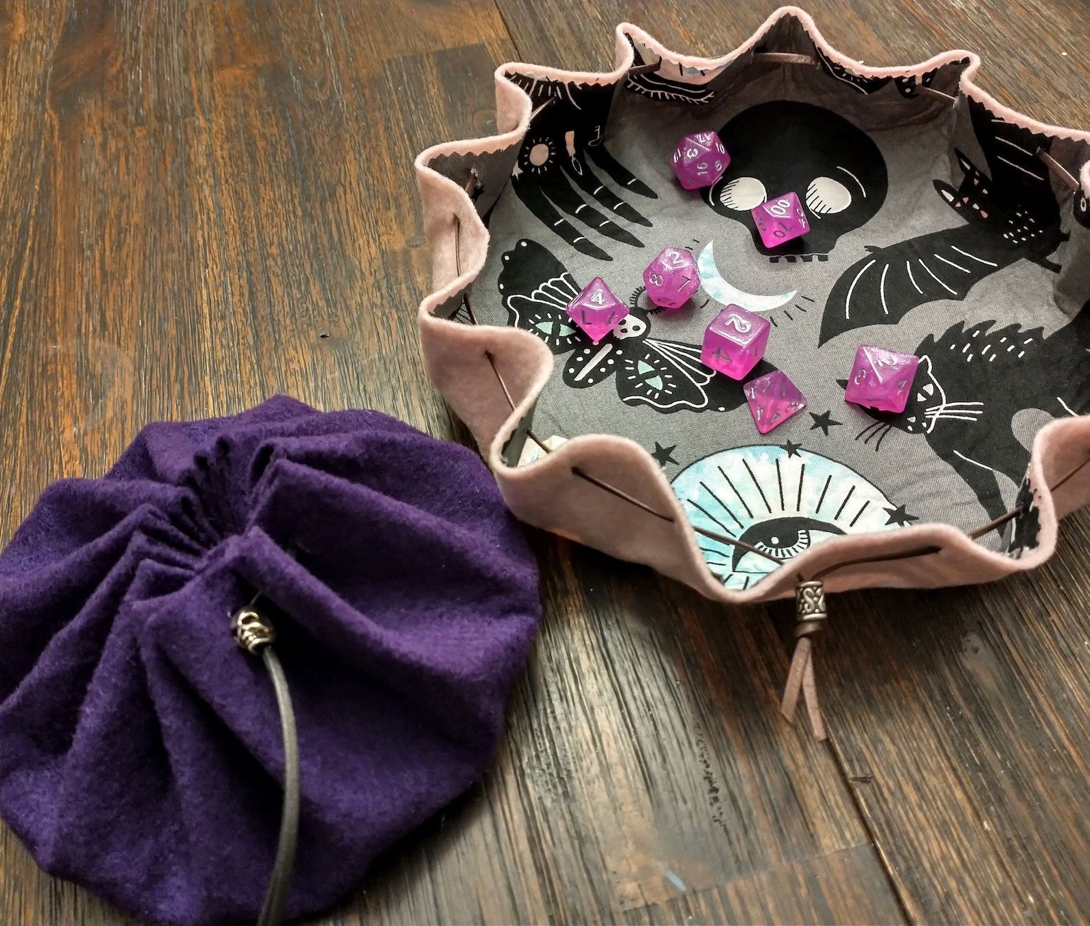 one open felt bag with dice and another closed felt bag are on a table. 