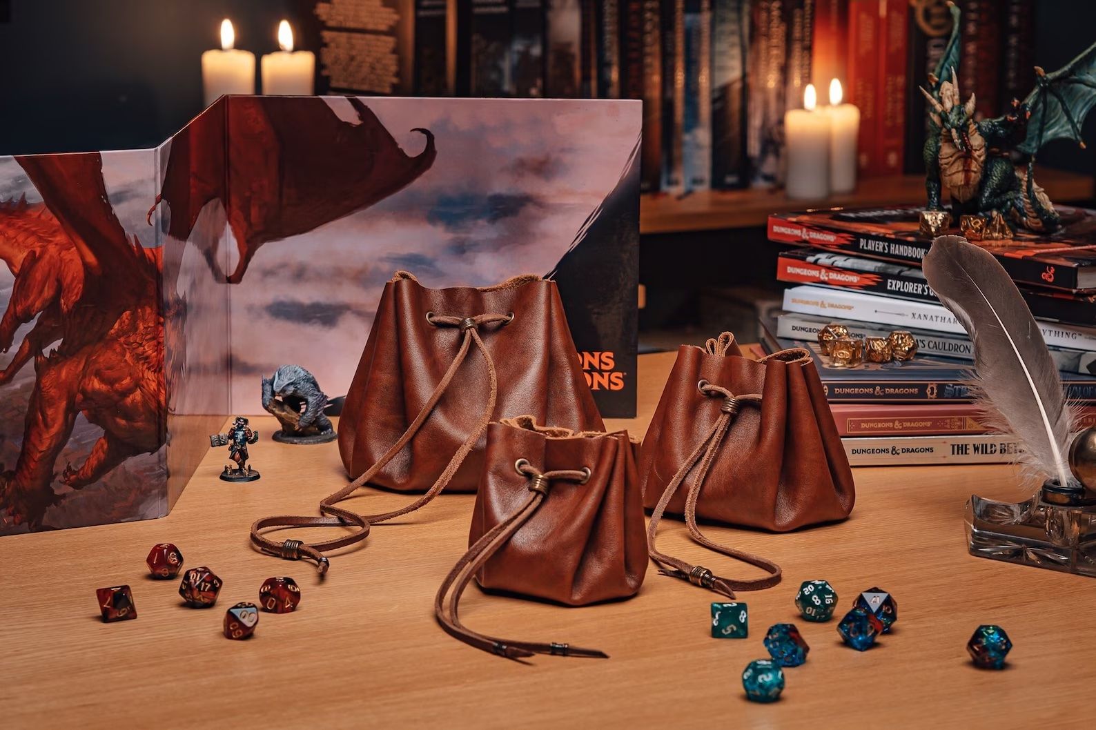 three leather dice bags on a table with dice, dnd books, and candles. 