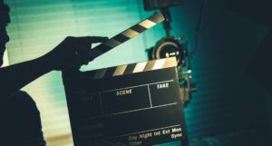 a shadowy image of a person on a film set about to snap a clapperboard in front of a camera