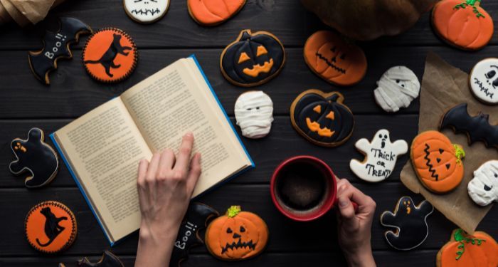 a person's hand in an open book surrounded by decorated cookies