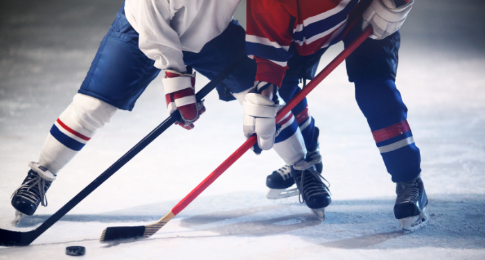 a photo of two hockey players both reaching for the puck