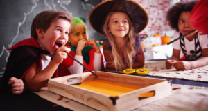 a photo of kids in Halloween costumes sitting at a table and smiling at something out of frame