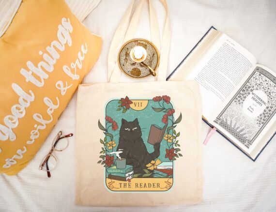 tote bag with a tarot card design showing a cat with a book and the text "The Reader" in the bottom