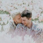 two white gay men nuzzling in a field of flowers