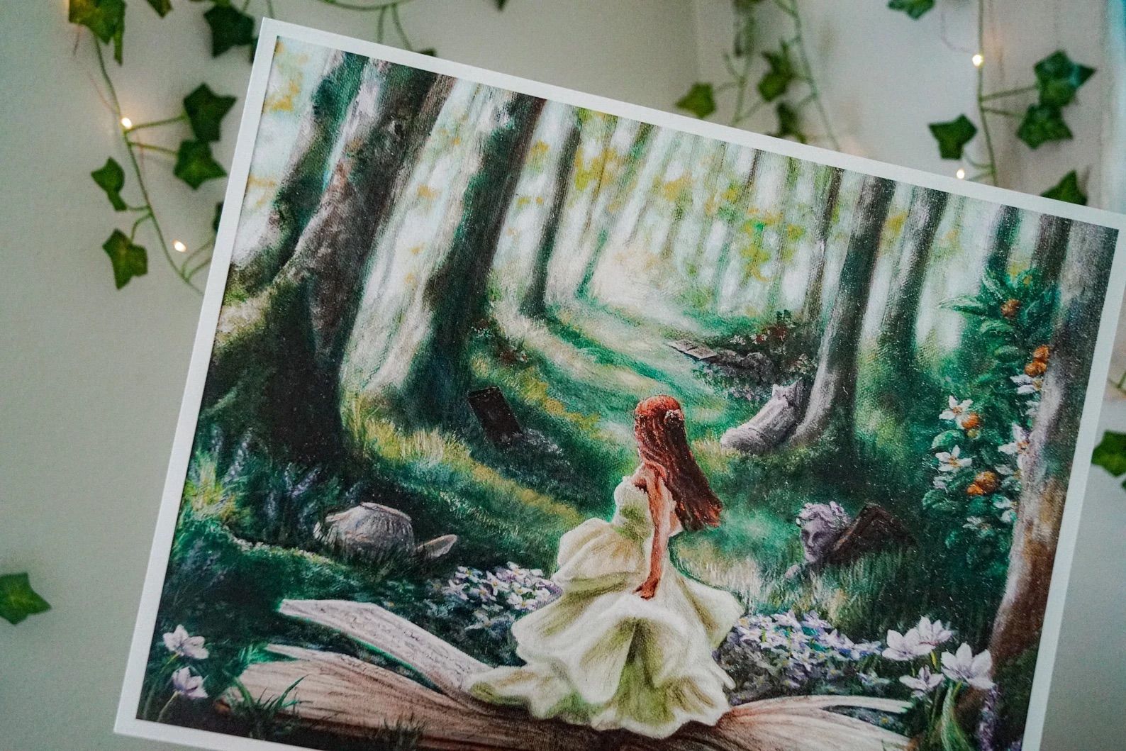 11x14 inch oil painting of a white girl in a white dress standing on an open book in the woods is in front of a wall with lights and vines.