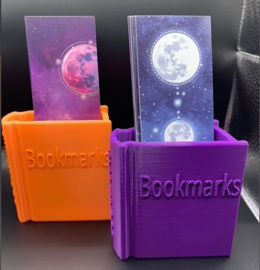 an orange and purple 3D printed bookmark holder in the shape of a book.