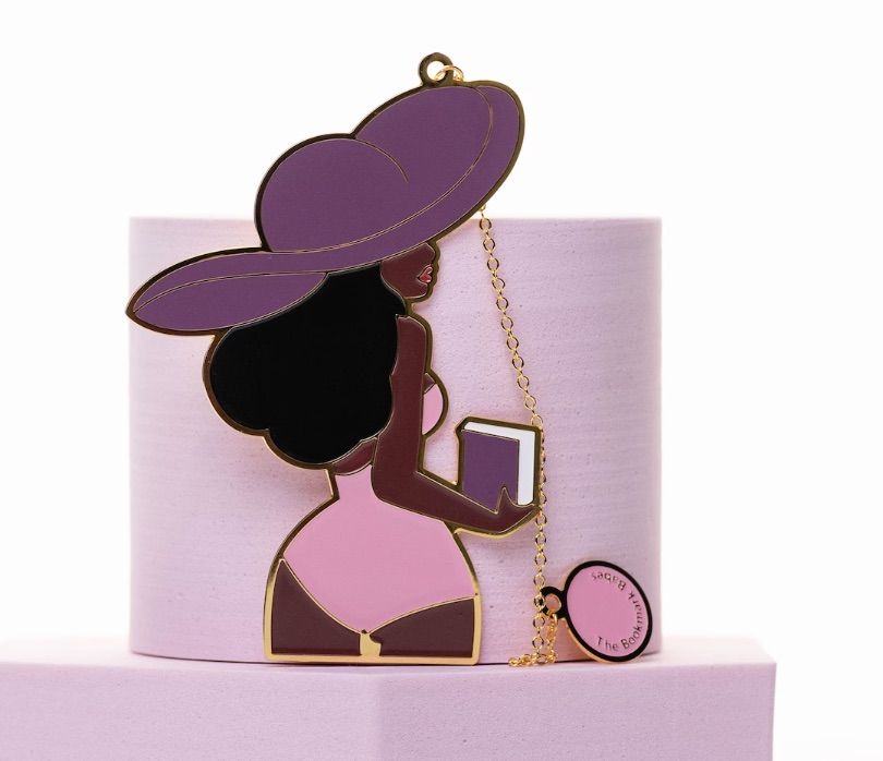 Image of a bookmark that is a Black woman wearing a bathing suit and beach hat. 