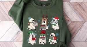 A green sweatshirt with various ghosts reading books and dressed with Santa hats, elf ears, reindeer antlers.
