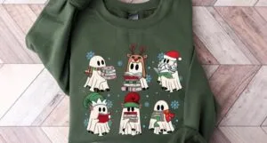 A green sweatshirt with various ghosts reading books and dressed with Santa hats, elf ears, reindeer antlers.