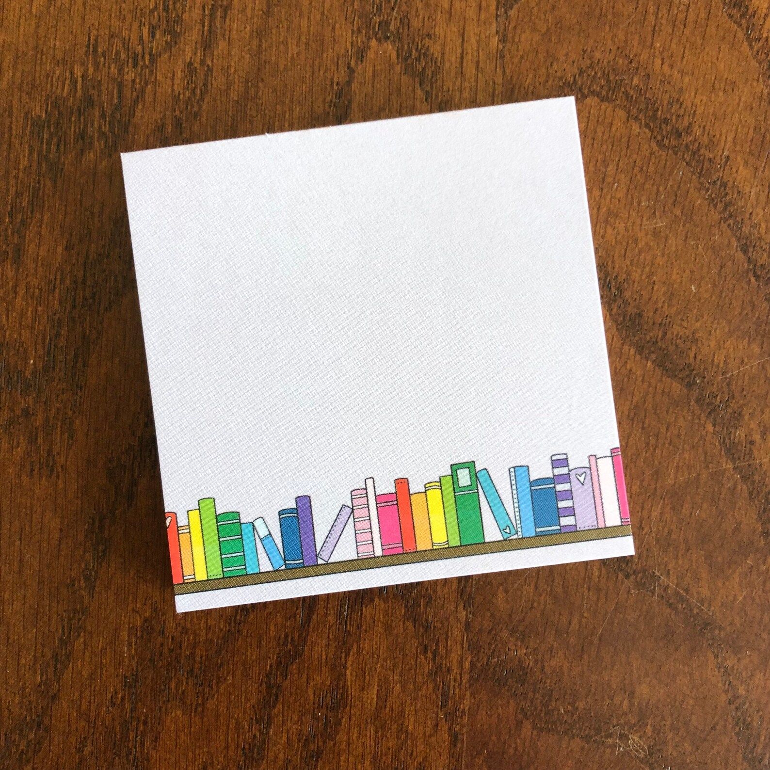 Image of a white pad of sticky notes with colorful books on it. 