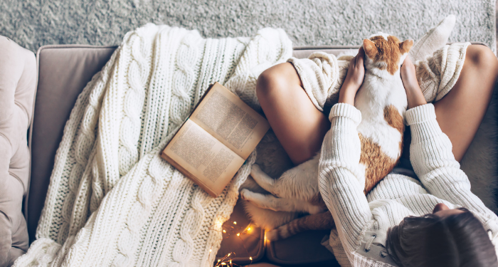 a photo of someone reading on the couch with a cat