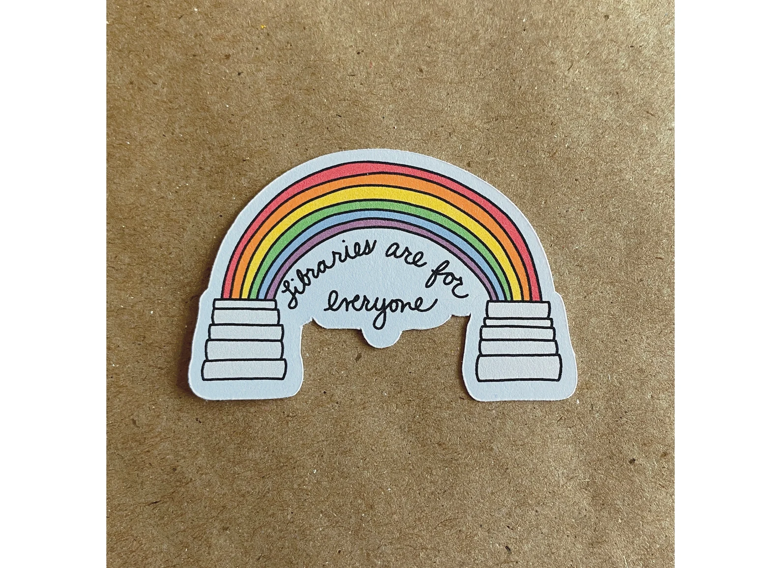 Image of two stacks of books with a rainbow connecting them, with the words "libraries are for everyone."