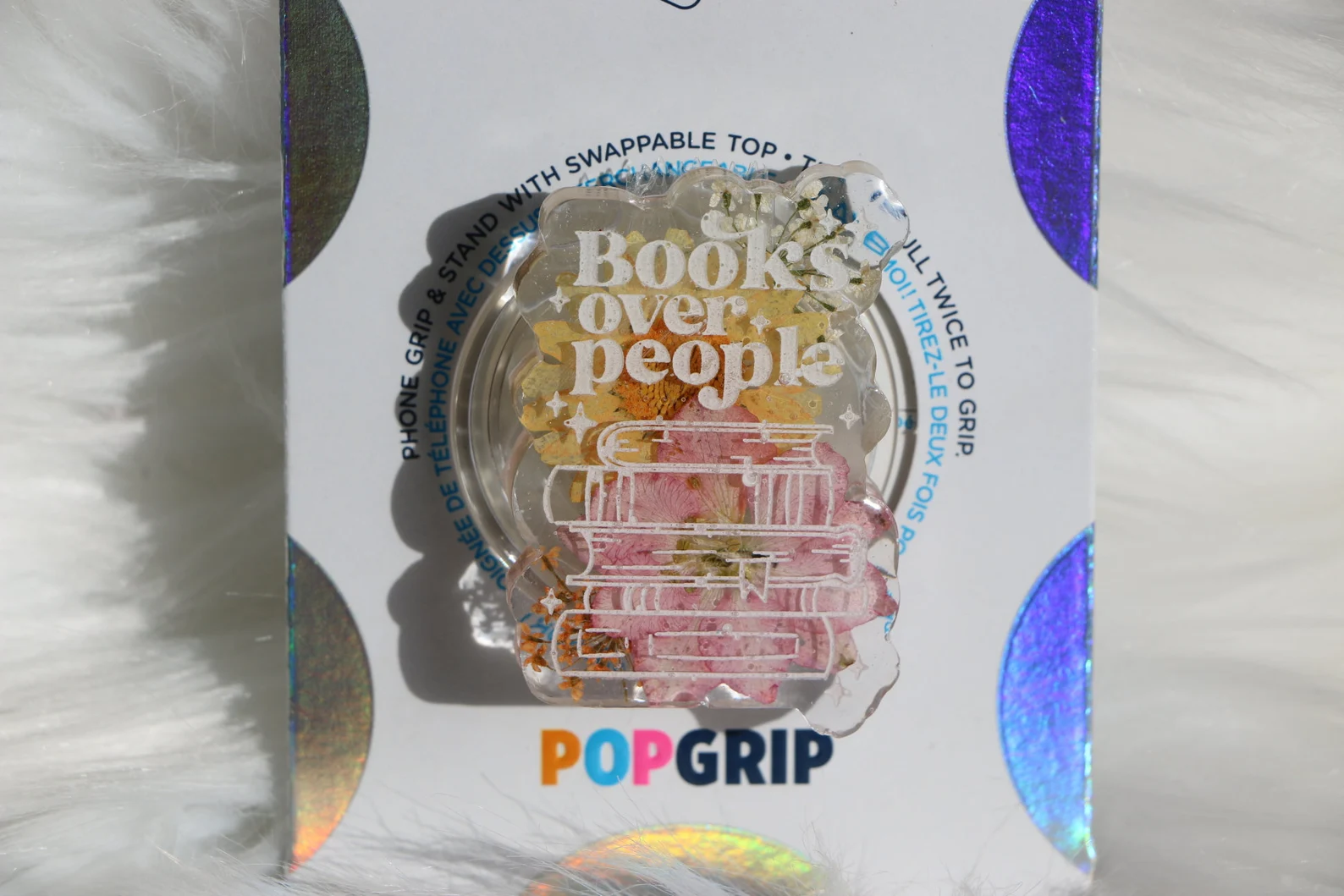 Image of a pop grip that features a stack of books and the words "books over people."