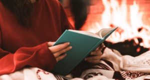 a photo of someone reading in bed with a fireplace in the background