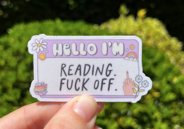a sticker illustrated like a name tag that says "hello I'm reading fuck off"