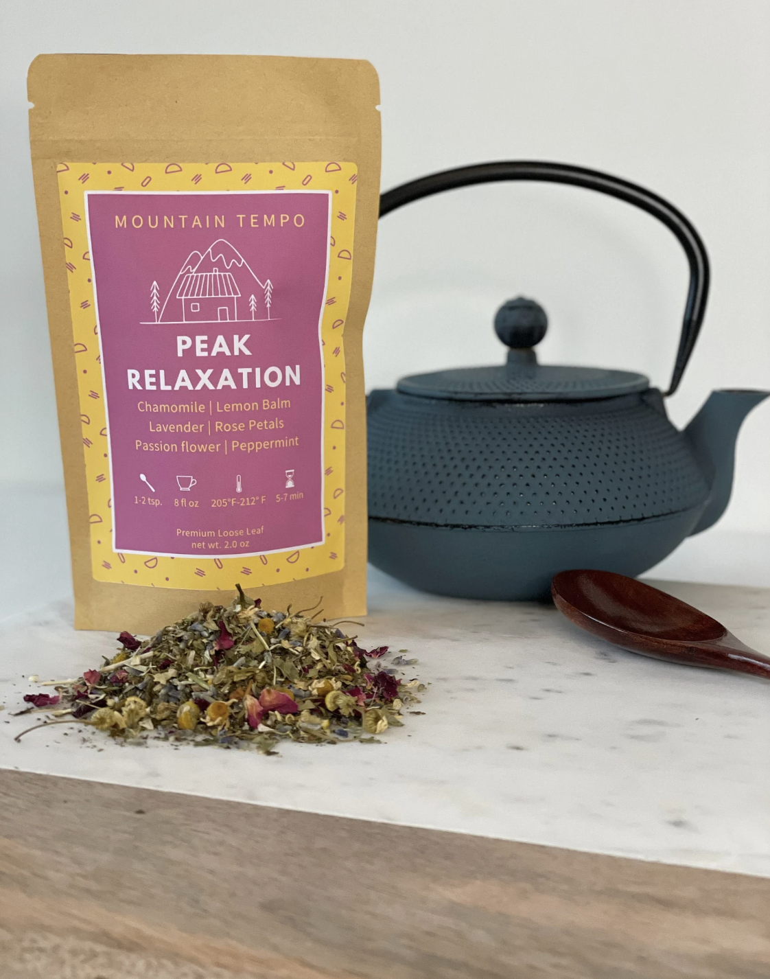 A bag of tea and a pile of looseleaf tea beside a gray teapot.