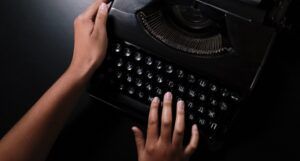 brown-skinned hands on an old fashioned typewriter