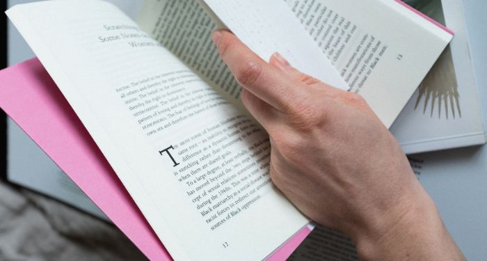 Image of a white hand holding open a book
