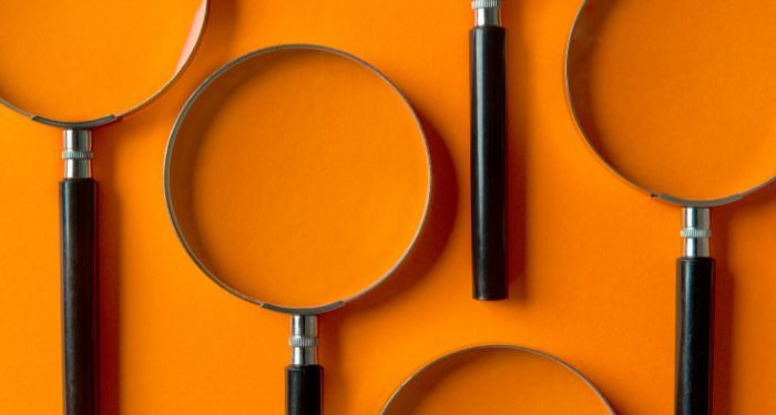 several magnifying glasses arranged against an orange background