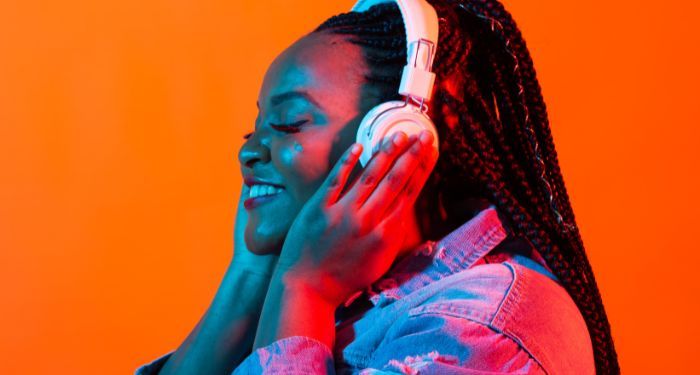 brown-skinned Black woman with box braids wearing headphones and smiling