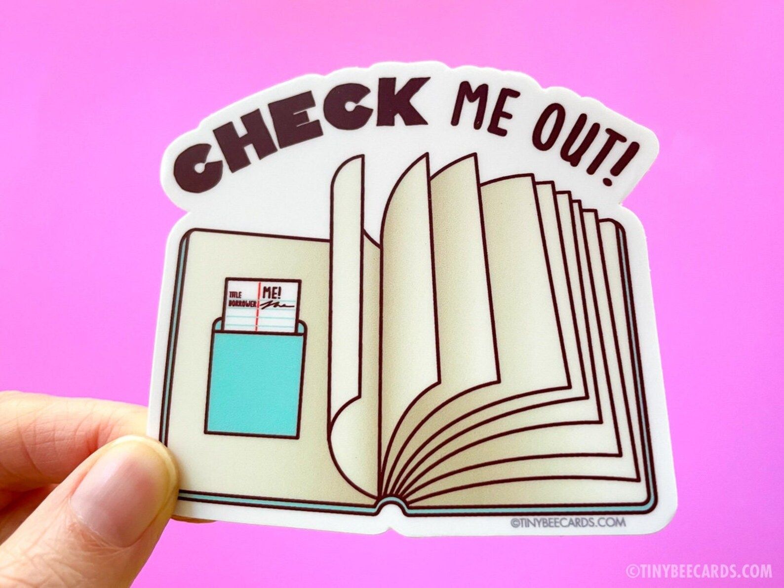 image of a book sticker with a due date card and the words "check me out."