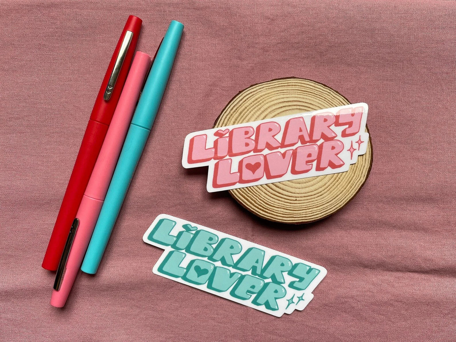 Image of two stickers, one pink and one green, in a retro font that say "library lover."